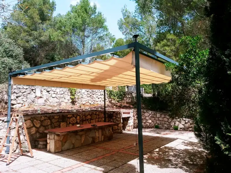 Toldo corredizo sobre estructura metálica autoportante en un jardín