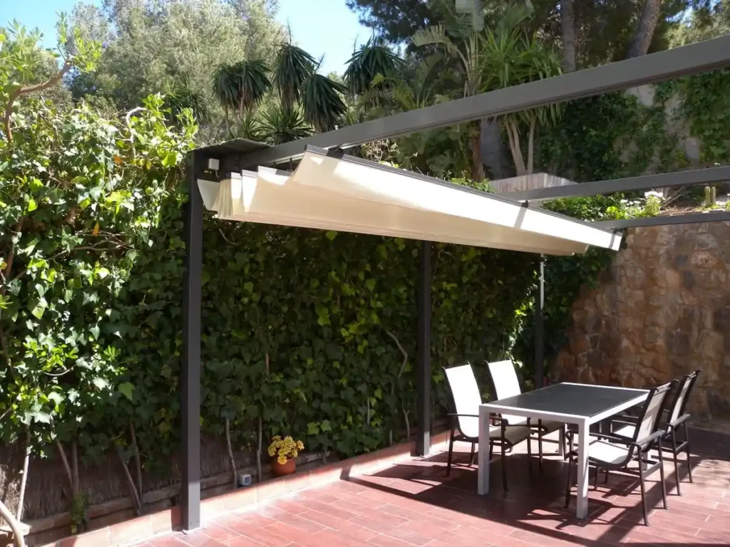 Toldo corredizo beige sobre estructura metálica en un patio con mesa
